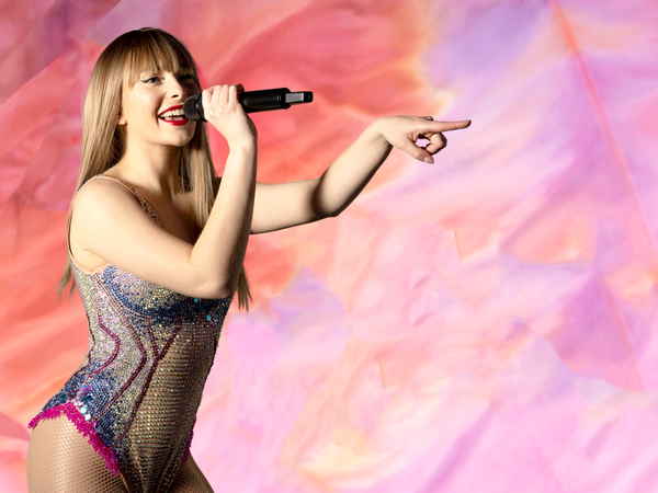 Taylor Swift tribute Glasgow smiling happily and pointing to audience during onstage tribute show | Altus Entertainment